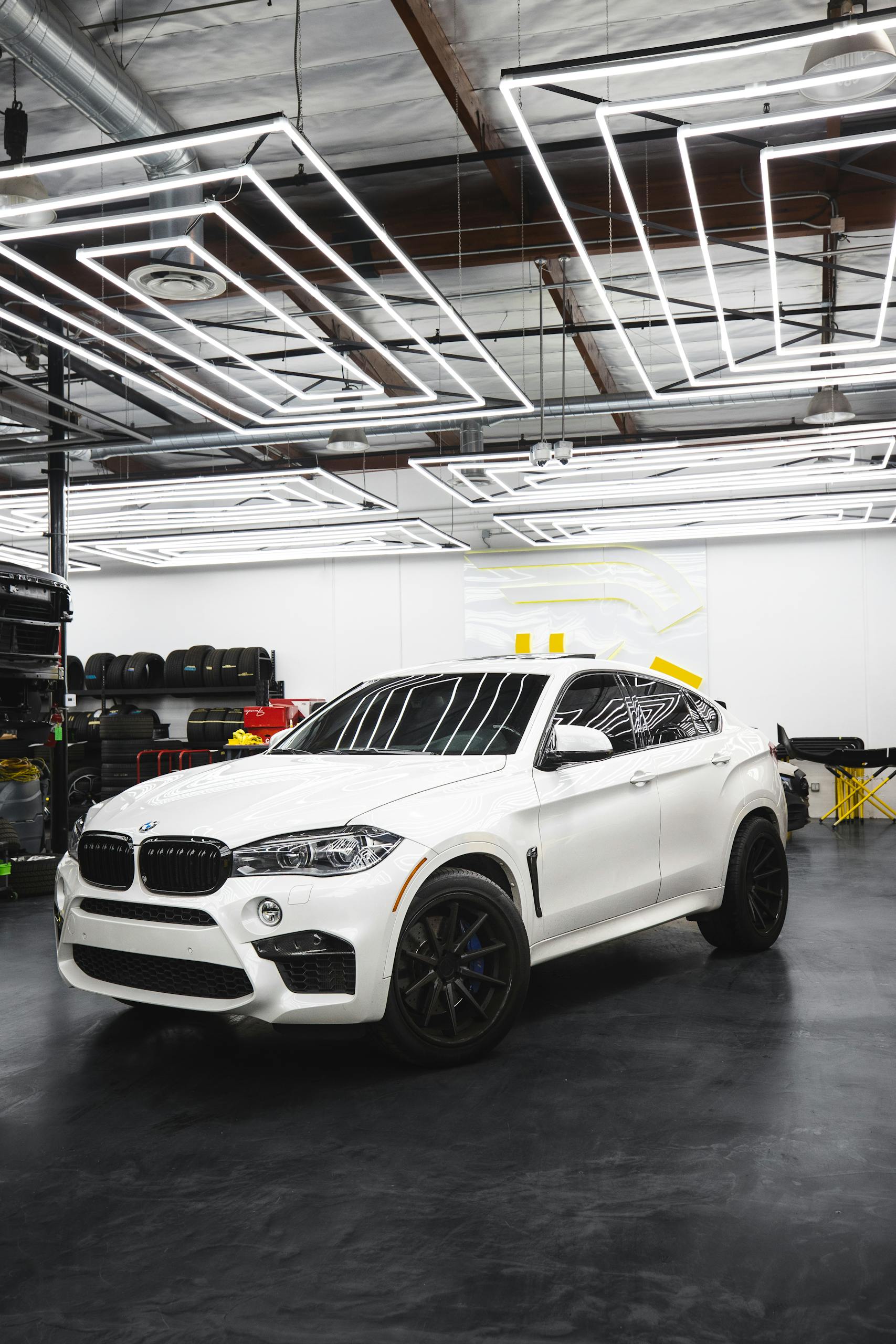 A sleek white BMW X6 parked in a contemporary auto repair shop setting.